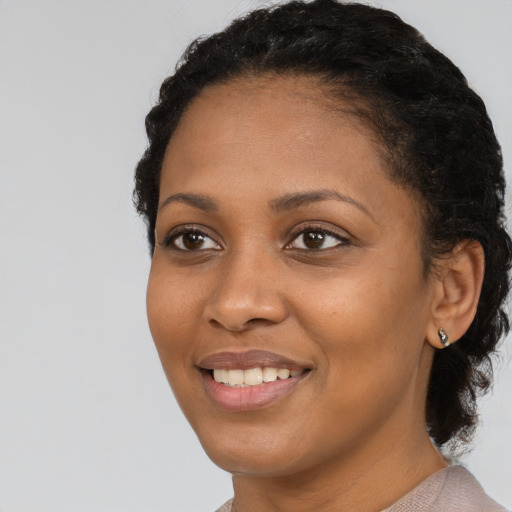 Joyful black young-adult female with short  black hair and brown eyes