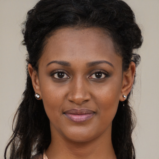 Joyful black young-adult female with long  black hair and brown eyes