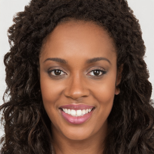 Joyful black young-adult female with long  brown hair and brown eyes