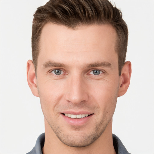 Joyful white young-adult male with short  brown hair and grey eyes