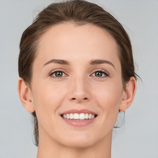 Joyful white young-adult female with medium  brown hair and grey eyes