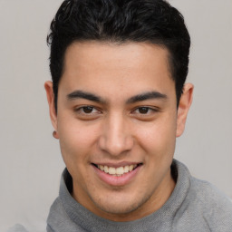 Joyful latino young-adult male with short  brown hair and brown eyes