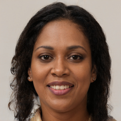 Joyful black young-adult female with long  brown hair and brown eyes