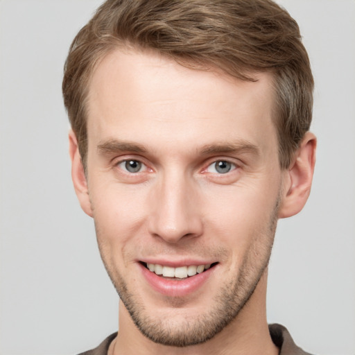 Joyful white young-adult male with short  brown hair and grey eyes