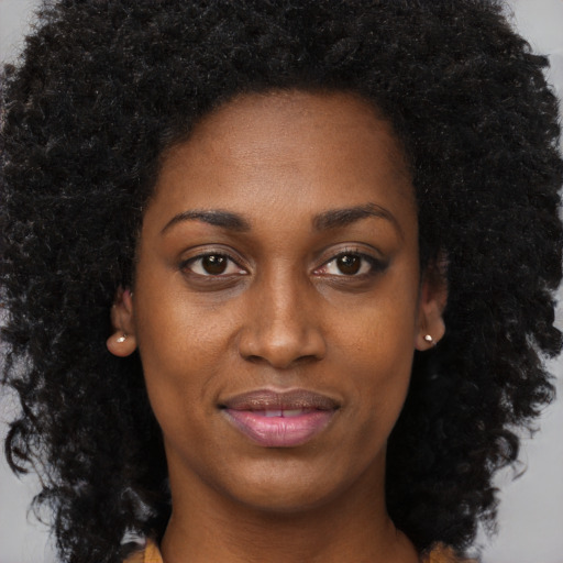 Joyful black young-adult female with long  brown hair and brown eyes