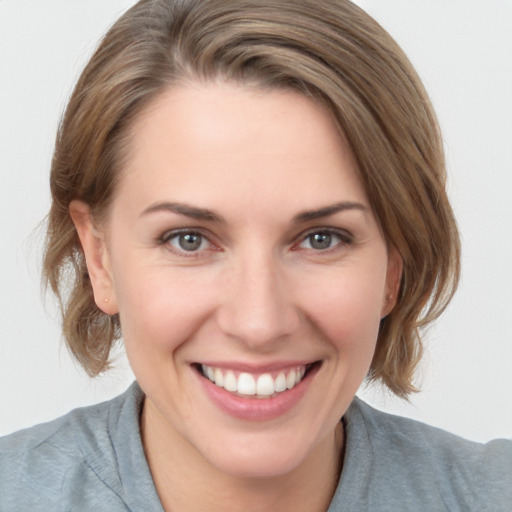 Joyful white young-adult female with medium  brown hair and grey eyes