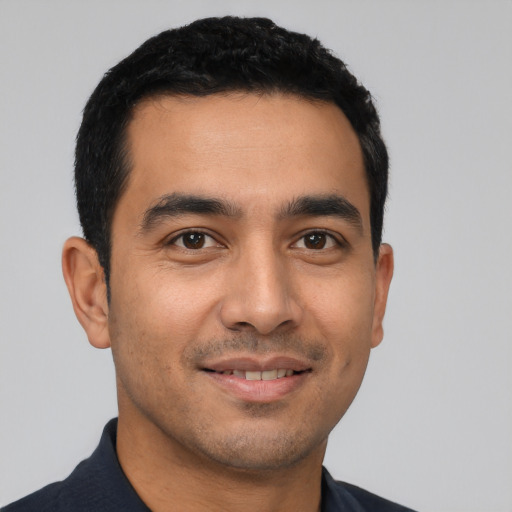 Joyful latino young-adult male with short  black hair and brown eyes