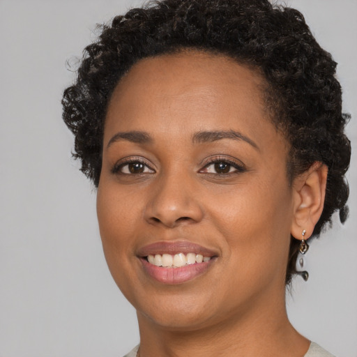 Joyful black young-adult female with short  black hair and brown eyes
