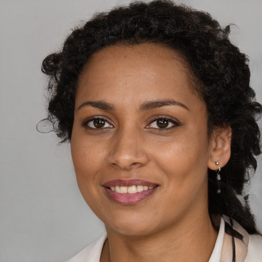 Joyful black young-adult female with long  brown hair and brown eyes