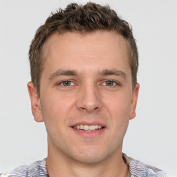 Joyful white young-adult male with short  brown hair and grey eyes