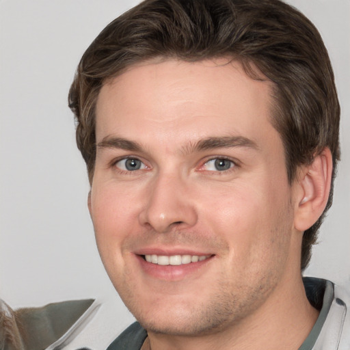 Joyful white young-adult male with short  brown hair and grey eyes