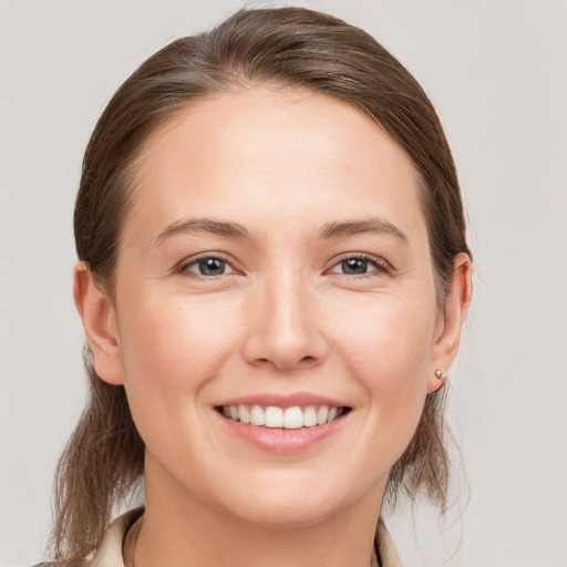 Joyful white young-adult female with medium  brown hair and grey eyes