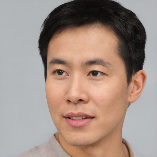 Joyful asian young-adult male with short  brown hair and brown eyes