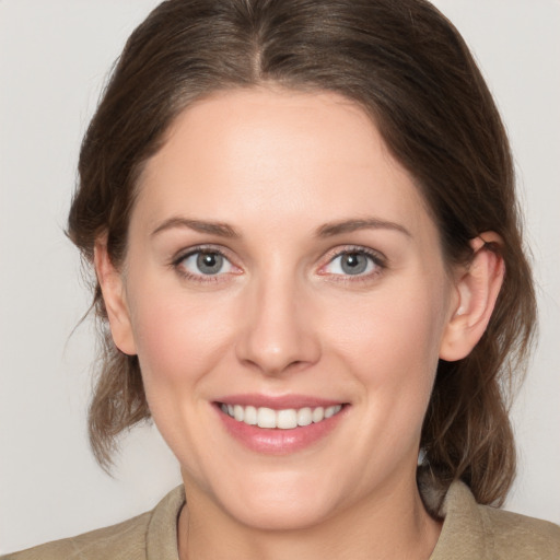 Joyful white young-adult female with medium  brown hair and grey eyes