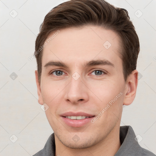 Joyful white young-adult male with short  brown hair and grey eyes