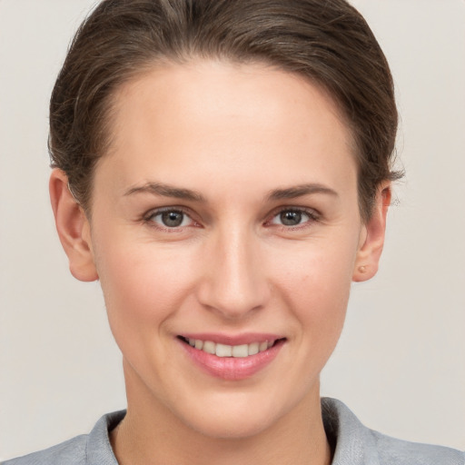 Joyful white young-adult female with short  brown hair and grey eyes