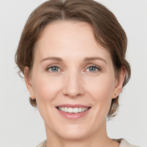 Joyful white young-adult female with medium  brown hair and grey eyes