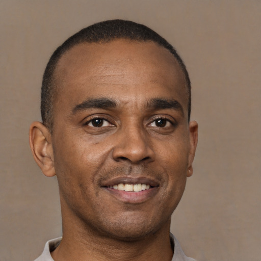 Joyful black young-adult male with short  brown hair and brown eyes