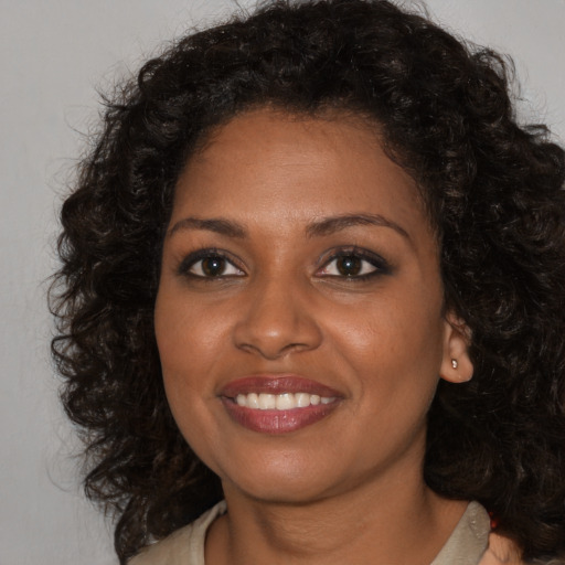 Joyful black young-adult female with long  brown hair and brown eyes