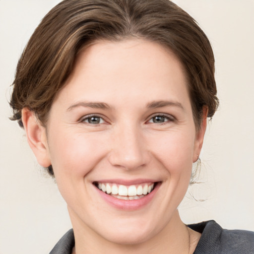 Joyful white young-adult female with medium  brown hair and grey eyes