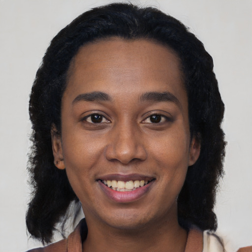 Joyful black young-adult female with long  black hair and brown eyes