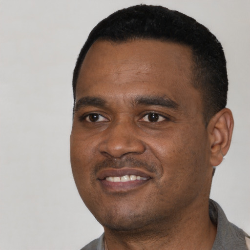 Joyful black young-adult male with short  black hair and brown eyes