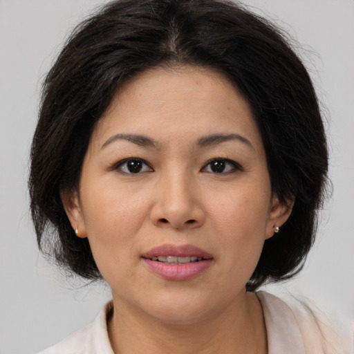 Joyful asian adult female with medium  brown hair and brown eyes