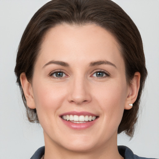 Joyful white young-adult female with medium  brown hair and grey eyes