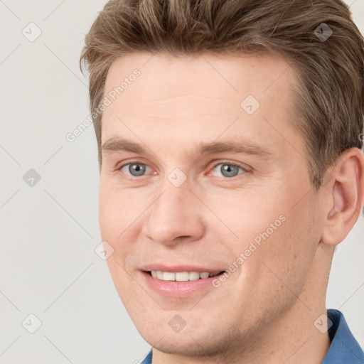 Joyful white young-adult male with short  brown hair and grey eyes