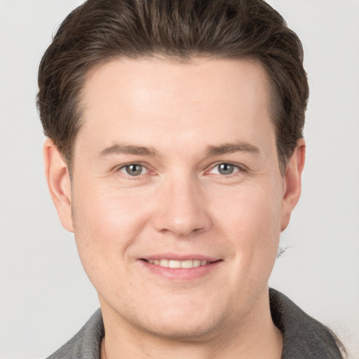 Joyful white young-adult male with short  brown hair and grey eyes