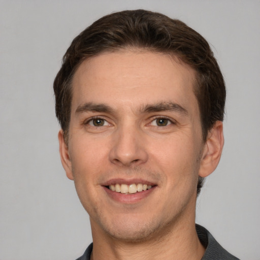 Joyful white young-adult male with short  brown hair and grey eyes