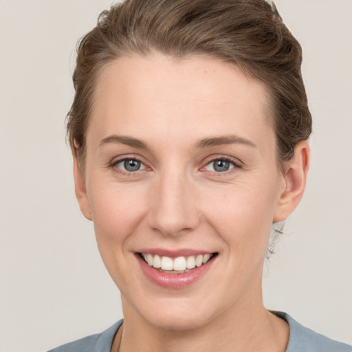 Joyful white young-adult female with short  brown hair and grey eyes