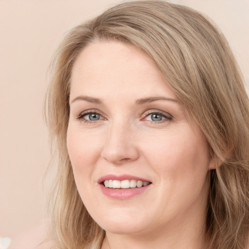 Joyful white adult female with long  brown hair and blue eyes