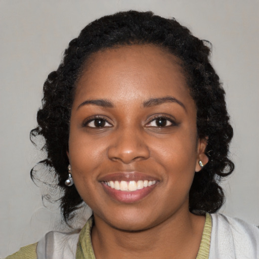 Joyful black young-adult female with long  black hair and brown eyes