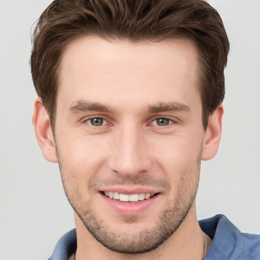 Joyful white young-adult male with short  brown hair and grey eyes