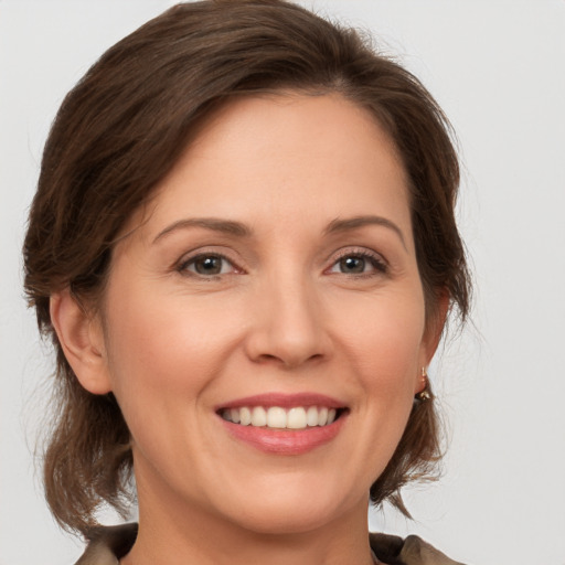 Joyful white young-adult female with medium  brown hair and grey eyes