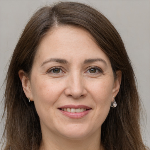 Joyful white adult female with long  brown hair and grey eyes