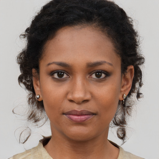 Joyful black young-adult female with long  brown hair and brown eyes