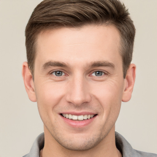 Joyful white young-adult male with short  brown hair and grey eyes