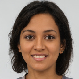 Joyful latino young-adult female with medium  brown hair and brown eyes