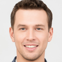 Joyful white young-adult male with short  brown hair and grey eyes