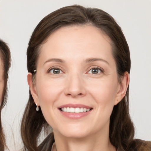 Joyful white young-adult female with long  brown hair and grey eyes