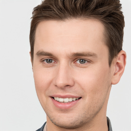 Joyful white young-adult male with short  brown hair and grey eyes