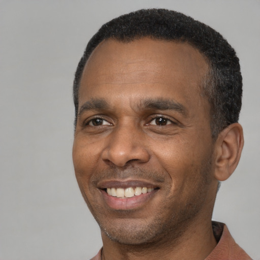 Joyful black adult male with short  black hair and brown eyes