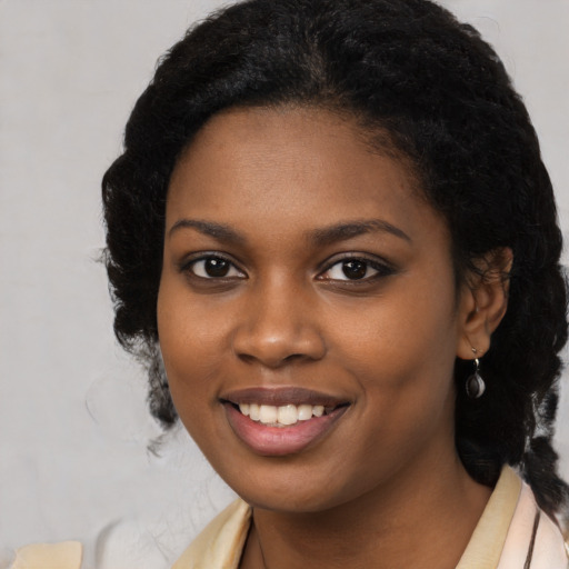 Joyful black young-adult female with long  black hair and brown eyes