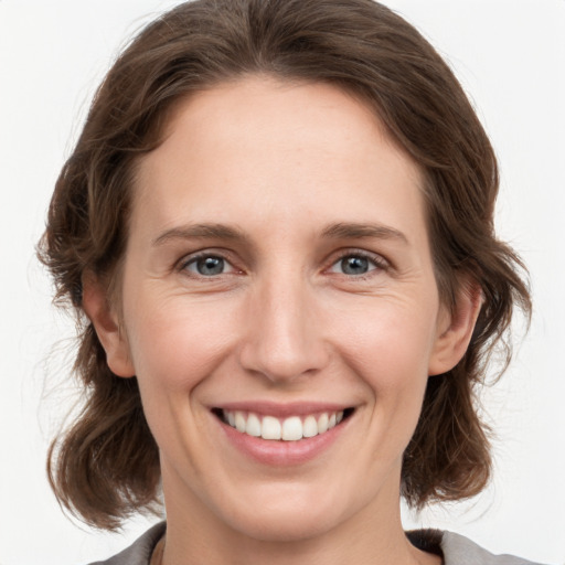 Joyful white young-adult female with medium  brown hair and grey eyes