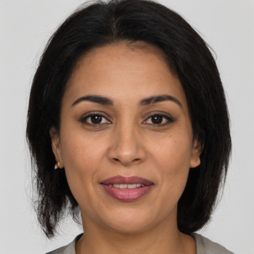 Joyful latino adult female with medium  brown hair and brown eyes