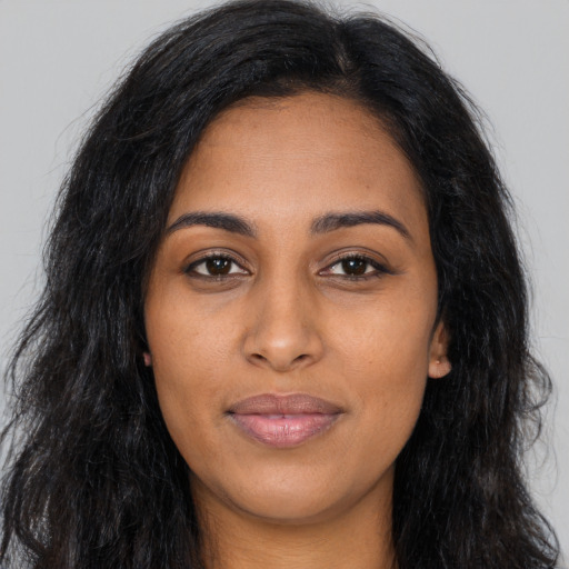 Joyful black young-adult female with long  brown hair and brown eyes
