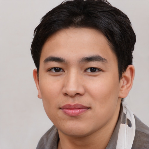 Joyful asian young-adult male with short  brown hair and brown eyes