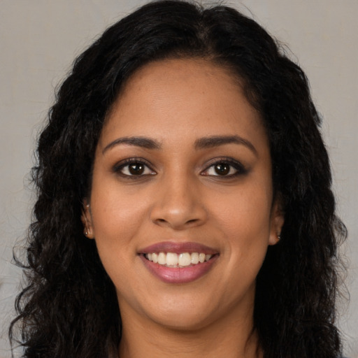 Joyful black young-adult female with long  black hair and brown eyes